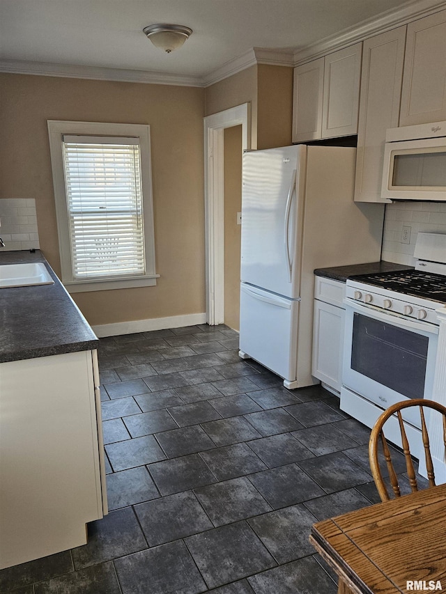 kitchen with dark countertops, ornamental molding, white appliances, and a sink