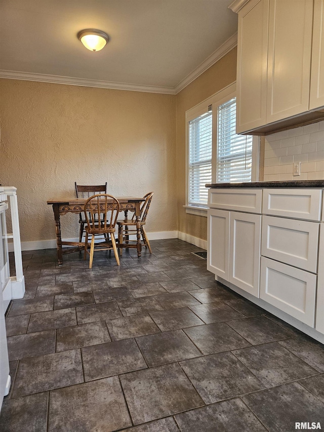 dining area featuring stone finish flooring, baseboards, and ornamental molding