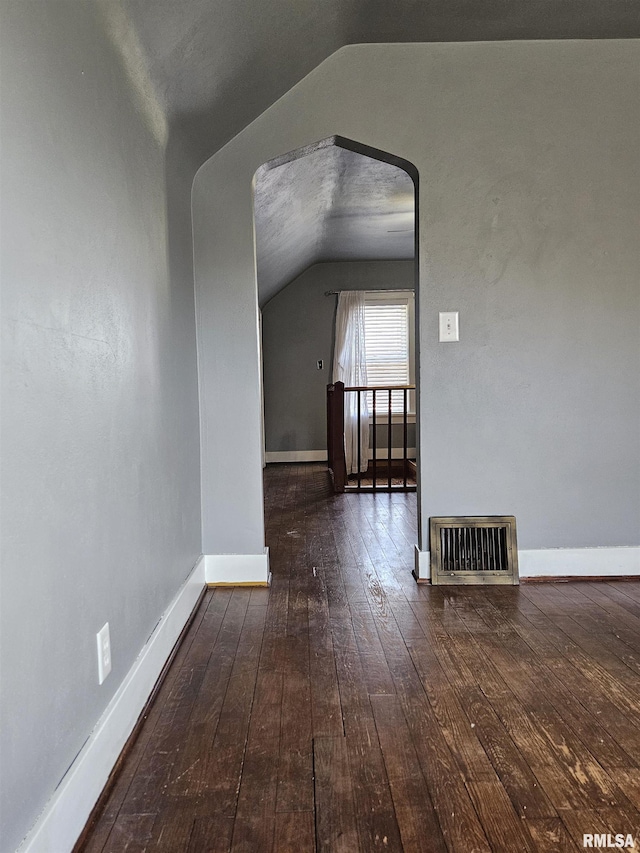 additional living space featuring visible vents, baseboards, lofted ceiling, and hardwood / wood-style flooring