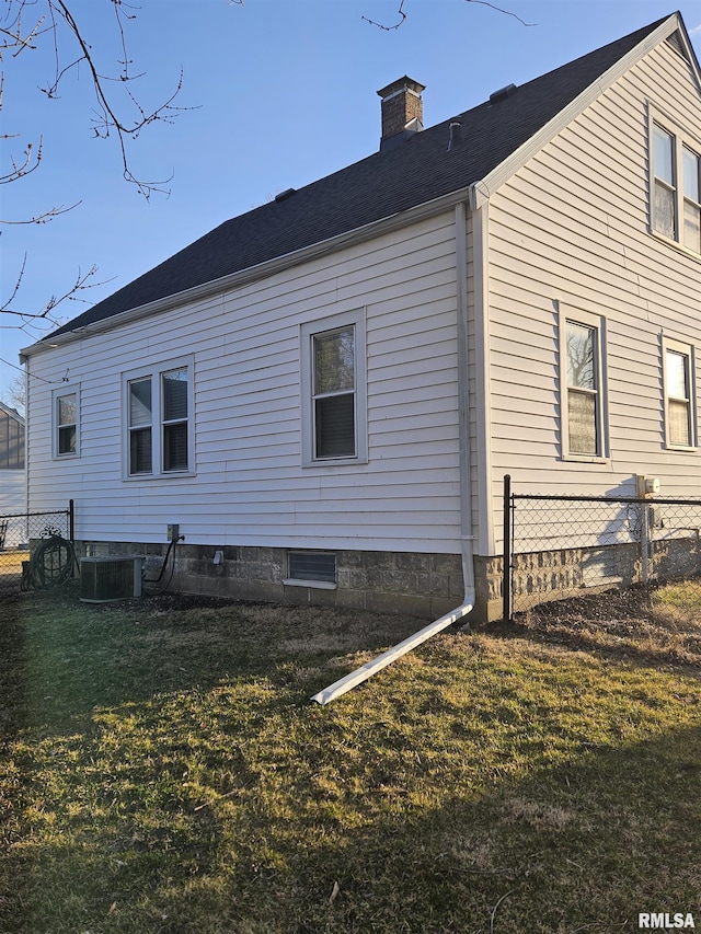 rear view of house with central AC unit, a chimney, a yard, and fence