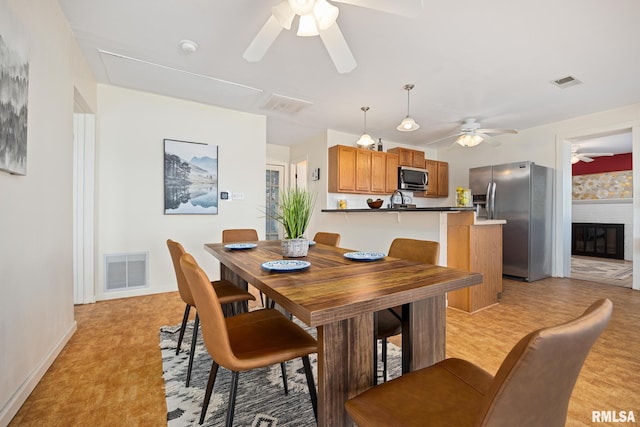 dining area featuring a ceiling fan, a fireplace, and visible vents