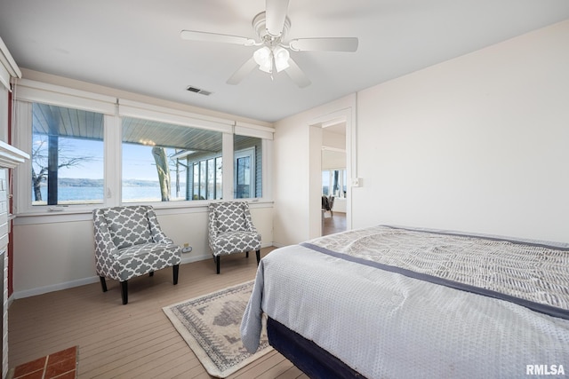 bedroom with visible vents, baseboards, ceiling fan, and hardwood / wood-style flooring