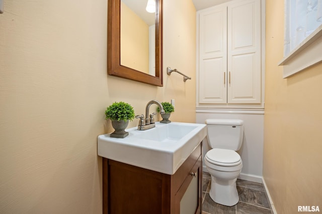 half bath with toilet, vanity, and baseboards