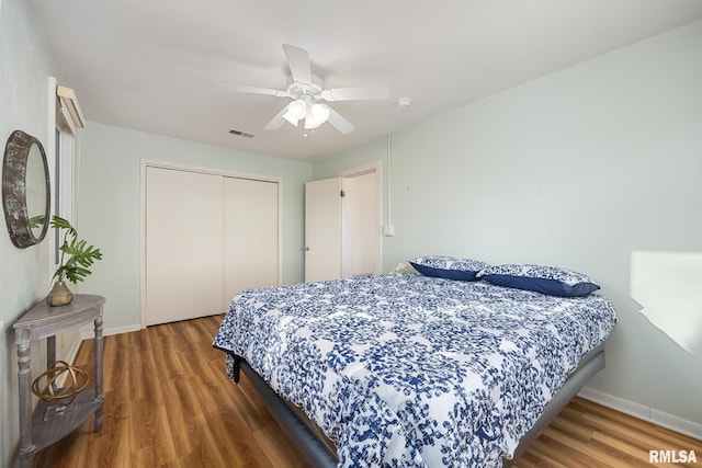 bedroom with a closet, visible vents, baseboards, and wood finished floors