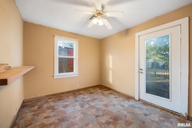 empty room with stone finish floor, baseboards, and ceiling fan