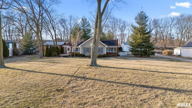 view of front facade featuring a front lawn and roof mounted solar panels