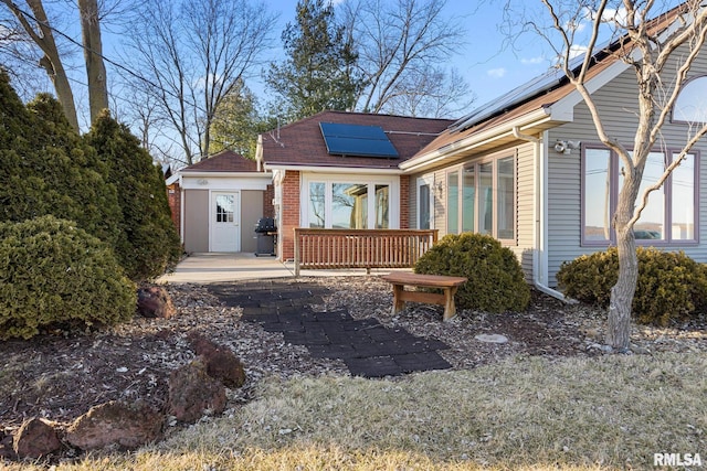 view of front of home featuring brick siding and roof mounted solar panels