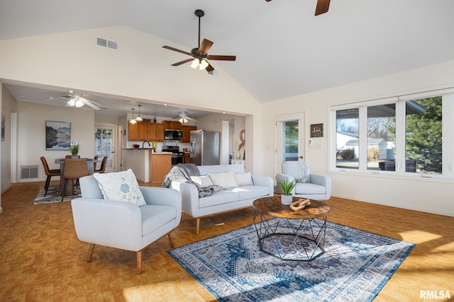 living room featuring visible vents, baseboards, high vaulted ceiling, and a ceiling fan