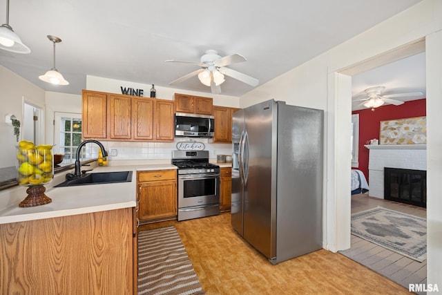 kitchen with a sink, ceiling fan, light countertops, stainless steel appliances, and brown cabinets