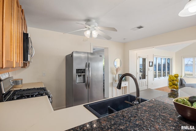 kitchen with visible vents, ceiling fan, appliances with stainless steel finishes, brown cabinetry, and a sink