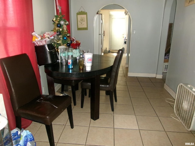 tiled dining room featuring baseboards and arched walkways