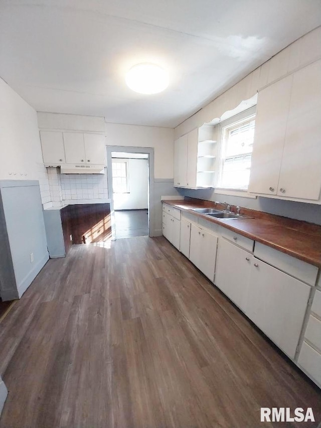 kitchen with a sink, a healthy amount of sunlight, white cabinets, and wood finished floors