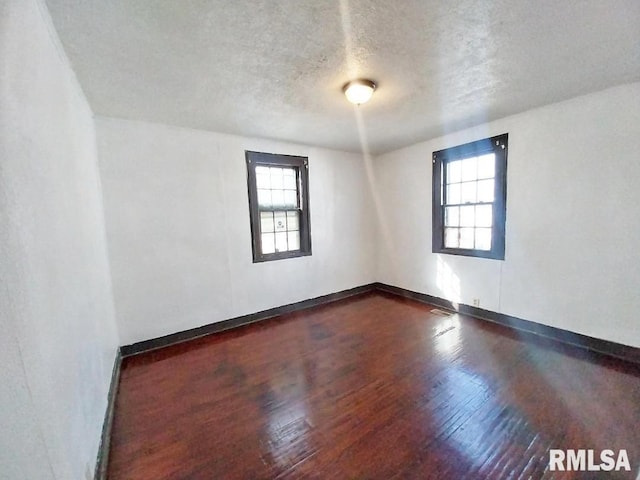 spare room featuring dark wood-style floors, baseboards, and a textured ceiling