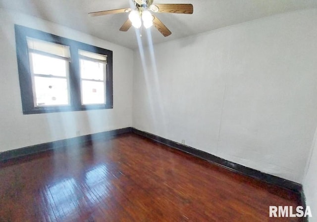 spare room with baseboards, a ceiling fan, and dark wood-style flooring