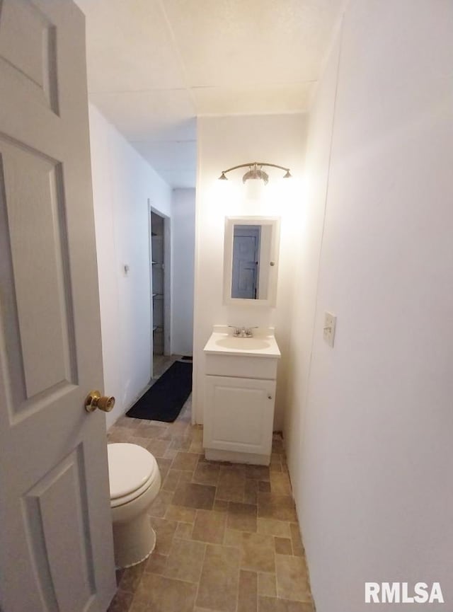 half bathroom featuring vanity, toilet, and stone finish flooring