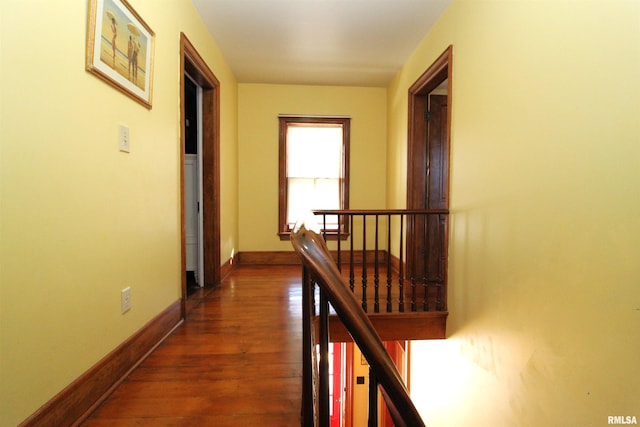 hall featuring baseboards, an upstairs landing, and dark wood finished floors