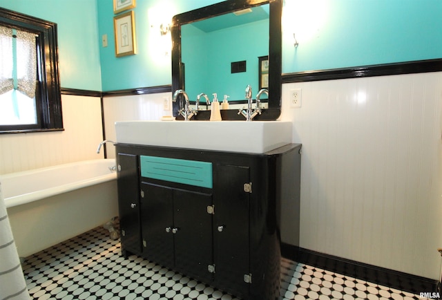 bathroom featuring vanity, a garden tub, and a wainscoted wall