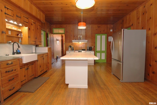 kitchen featuring light wood finished floors, freestanding refrigerator, a sink, light countertops, and wooden ceiling