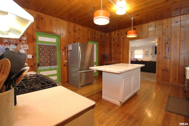 kitchen featuring light wood finished floors, wood ceiling, light countertops, and freestanding refrigerator