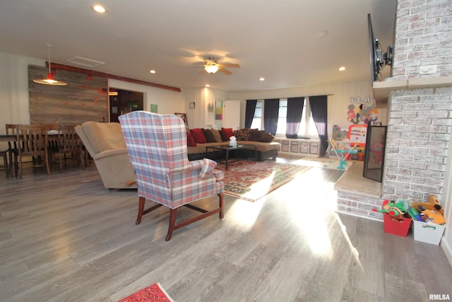 living room with a fireplace with raised hearth, recessed lighting, a ceiling fan, and wood finished floors