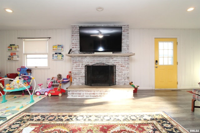 living room with wood finished floors, recessed lighting, and a fireplace