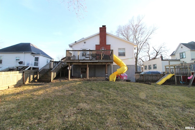 back of property with a yard, a playground, and a fenced backyard