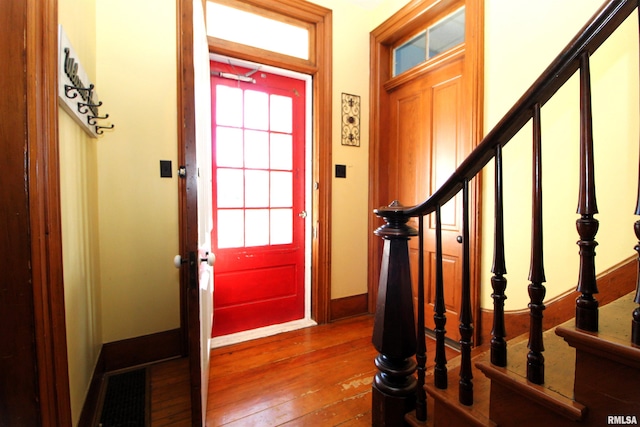 foyer entrance with stairs, hardwood / wood-style flooring, and baseboards