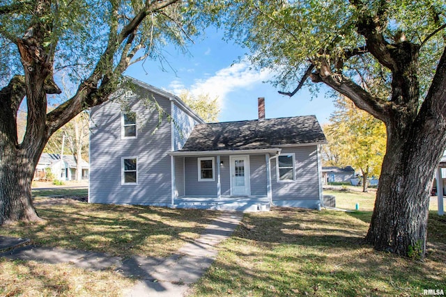 view of front of home featuring a porch, a chimney, a front lawn, and roof with shingles