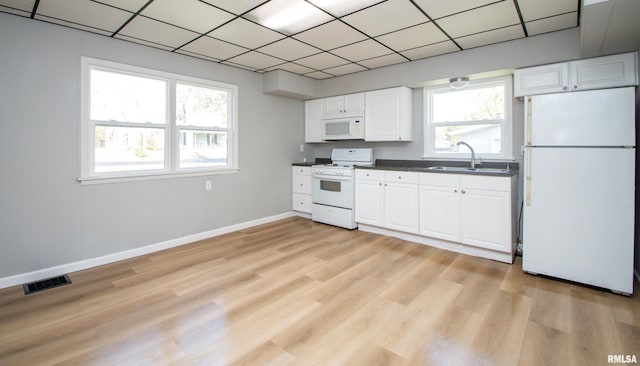 kitchen featuring visible vents, a sink, dark countertops, white appliances, and baseboards