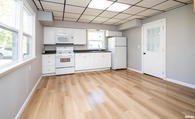 kitchen featuring white appliances, white cabinets, dark countertops, and a sink