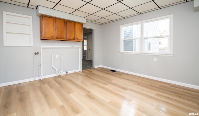 interior space featuring light wood finished floors, visible vents, built in shelves, and baseboards