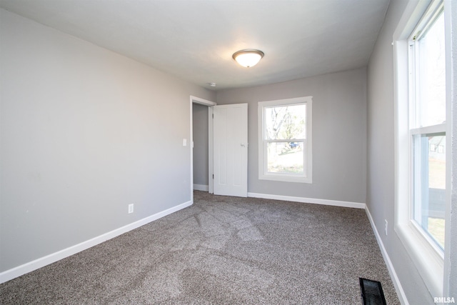 carpeted spare room with visible vents and baseboards