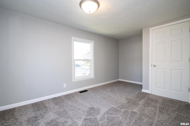 carpeted empty room featuring baseboards and visible vents