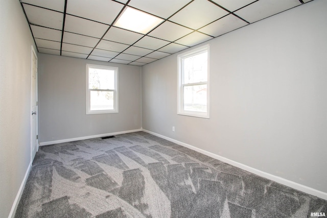 carpeted spare room with visible vents, a paneled ceiling, and baseboards