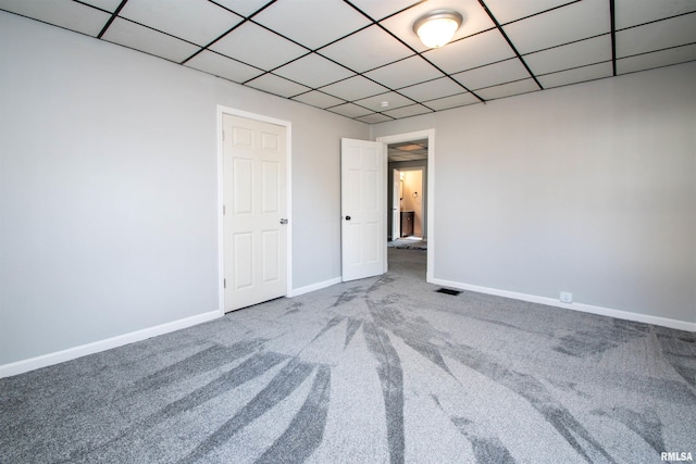 unfurnished bedroom with visible vents, carpet flooring, a paneled ceiling, and baseboards