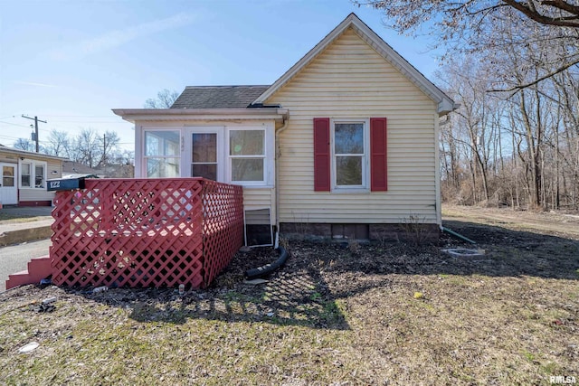 rear view of house with a shingled roof and a sunroom