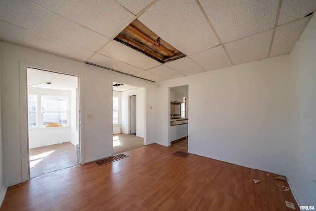 spare room featuring visible vents, wood finished floors, and a drop ceiling