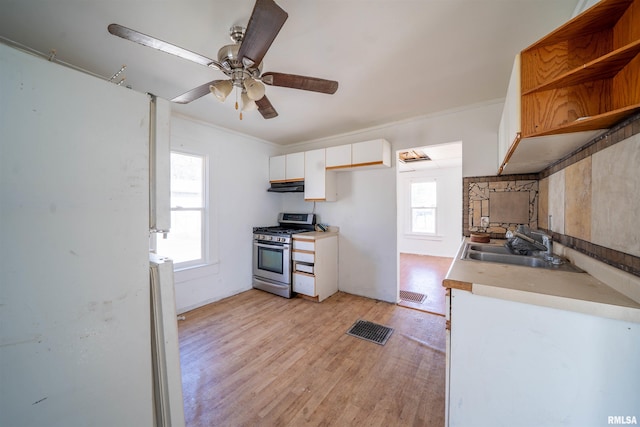 kitchen featuring stainless steel gas range, open shelves, a sink, white cabinetry, and light wood-type flooring