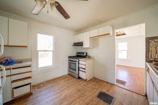 kitchen featuring under cabinet range hood, visible vents, gas range, and light wood finished floors