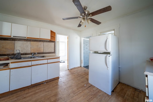 kitchen featuring open shelves, freestanding refrigerator, light countertops, white cabinets, and light wood-style floors