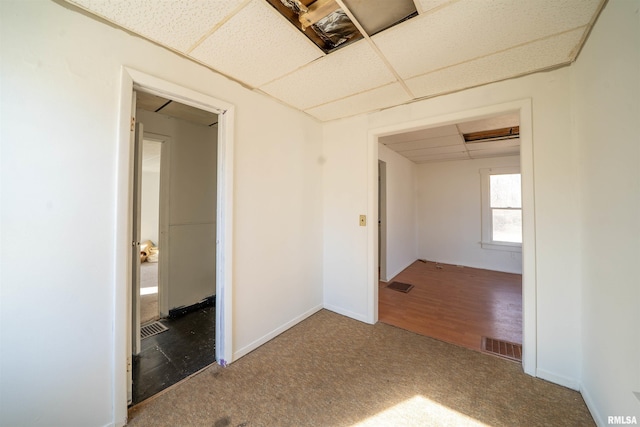 spare room with visible vents, baseboards, carpet, and a drop ceiling