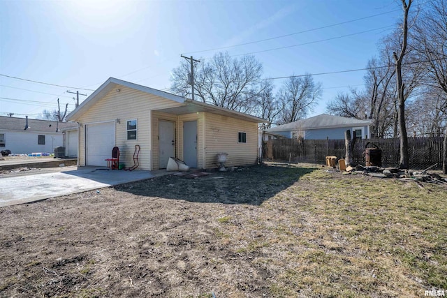 exterior space with an outbuilding, concrete driveway, and fence