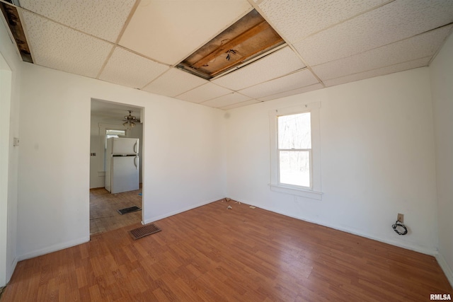 unfurnished room featuring a drop ceiling, visible vents, and wood finished floors