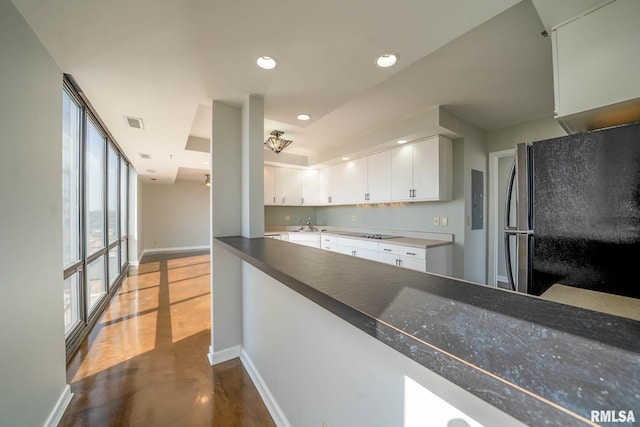 kitchen with baseboards, finished concrete floors, recessed lighting, freestanding refrigerator, and white cabinets