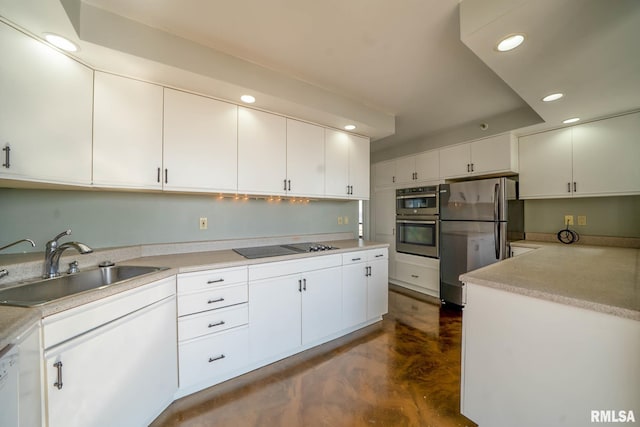 kitchen featuring recessed lighting, a sink, light countertops, appliances with stainless steel finishes, and white cabinetry