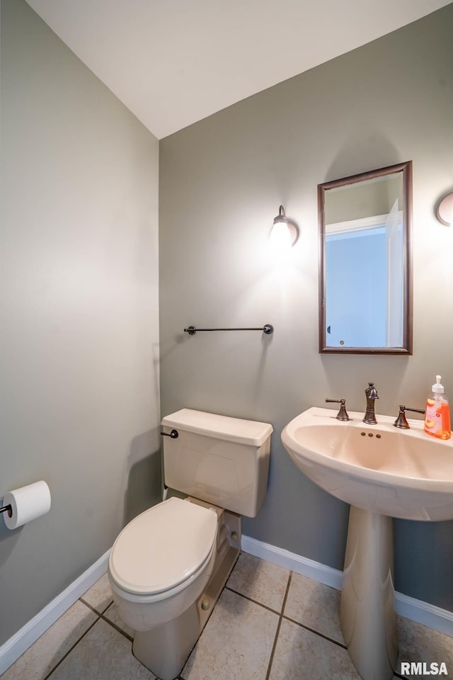 half bath featuring a sink, baseboards, toilet, and tile patterned flooring