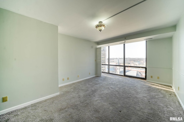 carpeted spare room featuring visible vents, a wall of windows, and baseboards