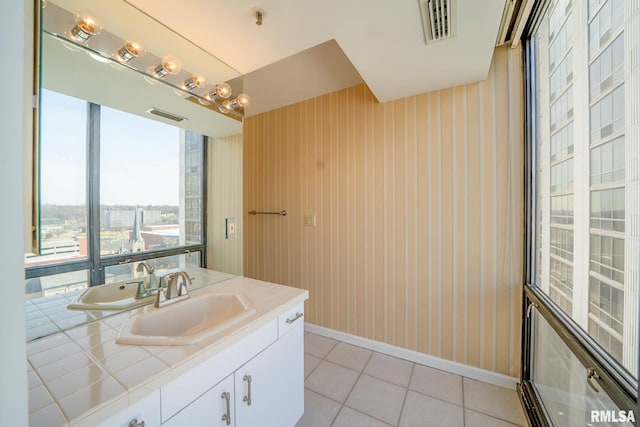 bathroom featuring tile patterned floors, visible vents, a view of city, baseboards, and vanity