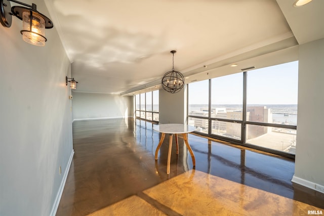 unfurnished dining area with baseboards, a notable chandelier, a city view, and finished concrete floors