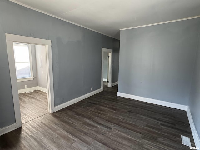 unfurnished room featuring dark wood-style floors, visible vents, crown molding, and baseboards